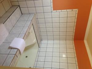 baño de azulejos blancos con bañera y aseo en Value Inn, en Sylmar