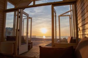 een open deur naar het strand bij zonsondergang bij Surf en beach strandhuisjes in Katwijk +2 foto's