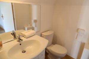 uma casa de banho branca com um WC e um lavatório em Le Four à Pain em Leynhac