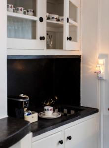 een keuken met witte kasten en een zwart aanrecht bij SWEETS - Kinkerbrug in Amsterdam