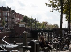 una mujer sentada en un banco junto a un canal en SWEETS - Kinkerbrug, en Ámsterdam 10 fotos más