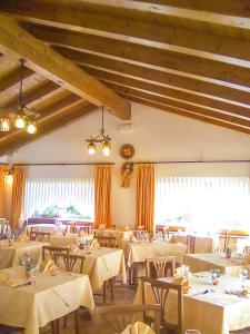 um restaurante com mesas e cadeiras brancas e uma grande janela em Albergo Larese em Auronzo di Cadore