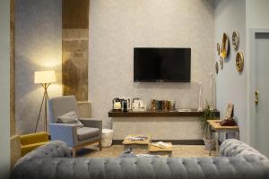 a living room with a couch and a tv on a wall at Petit Palace Plaza del Carmen in Madrid