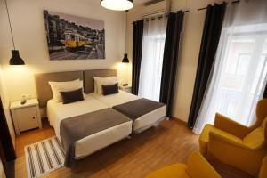a bedroom with a large bed and a yellow chair at Anjo Azul in Lisbon