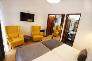 a bedroom with a bed and two chairs and a television at Anjo Azul in Lisbon
