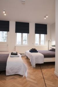 two beds in a bedroom with windows and wooden floors at Kuwadro Guesthouse Centrum in Amsterdam