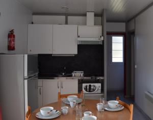 cocina con mesa de madera y armarios blancos en Camping - Village Vacances du Lac, en Boulogne-sur-Gesse