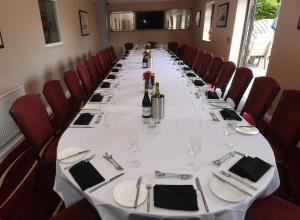 Spanhoe Lodge في Harringworth: طاولة طويلة في غرفة مع كراسي حمراء