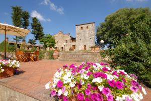 un giardino fiorito di fronte a un castello di B&B La Torre - Fattoria di Larniano a San Gimignano
