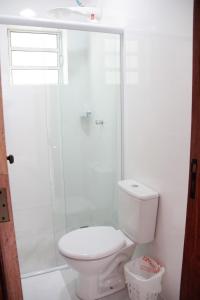 a white bathroom with a toilet and a shower at Souza Reis Flat in São Thomé das Letras