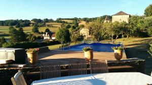 a patio with a table and chairs and a swimming pool at Le Cayla in Leynhac