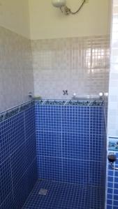 a bathroom with blue tiled walls and a shower at Chalézinho - Massaguaçu in Caraguatatuba
