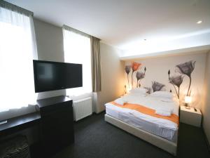a hotel room with a bed, tv, and desk at City Park Hotel in Bila Tserkva