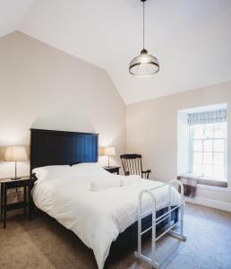 1 dormitorio con 1 cama blanca grande y 1 silla en Orchard Cottage en St Andrews
