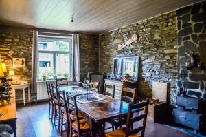 a dining room with a wooden table and a stone wall at B&B Au Canard in La-Roche-en-Ardenne