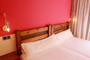1 dormitorio con cama blanca y pared roja en Apartamentos Alda Porta do Sol, en Vigo