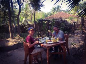 Ein Mann und eine Frau sitzen am Tisch und essen Essen. in der Unterkunft Yapahuwa Relax Stay in Yapahuwa