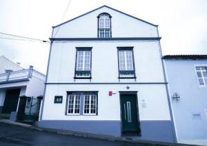 un edificio blanco con una puerta verde y ventanas en Cantinho do Pensamento, en Ribeira Grande