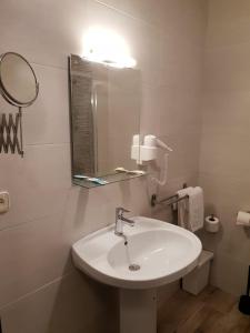 Baño blanco con lavabo y espejo en Complejo Hotelero Saga, en Manzanares