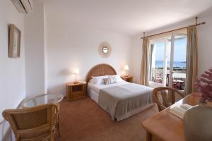 a bedroom with a bed and a view of the ocean at Hotel Le Tilbury in Porto-Vecchio