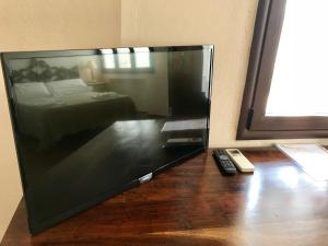 TV de pantalla plana grande con suelo de madera en Hotel Su Meriagu, en Capitana