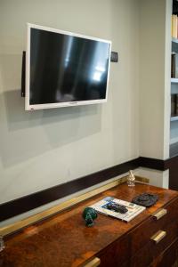 TV de pantalla plana en una pared sobre una mesa de madera en Two Sisters Suites, en Nápoles