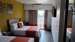 a hotel room with two beds and a television at Terrass Hotel Zamora in Zamora de Hidalgo