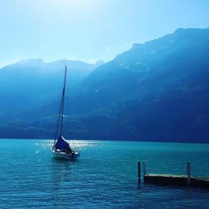 un velero en el agua cerca de un muelle en Chalet Diana Lakefront en Ringgenberg