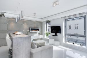 a white living room with a tv and a couch at Elite Apartments Prestige Old Town in Gdańsk