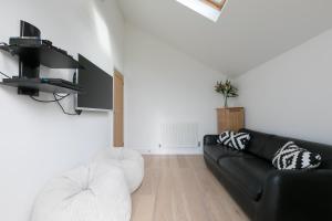 sala de estar con sofá negro y sillas blancas en Tara en St Ives