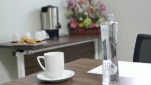 a table with a coffee cup and a bottle of water at Terrass Hotel Zamora in Zamora de Hidalgo