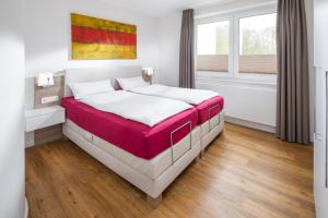 诺德奈Storchennest Norderney的一间卧室配有一张铺有白色和红色床单的床