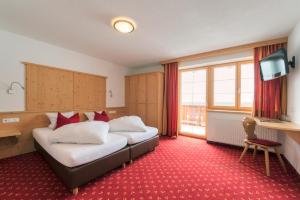 a hotel room with two beds and a television at Bacherhof in Sankt Anton am Arlberg