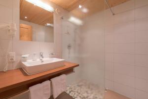 a white bathroom with a sink and a shower at Bacherhof in Sankt Anton am Arlberg