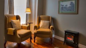a living room with two chairs and a fire place at Sir Isaac Brock B&B Luxury Suites in Brockville