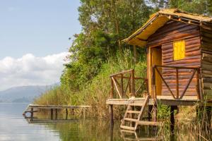 a wooden cabin on the water with a dock at OM Hostel Bunyonyi in Kabale