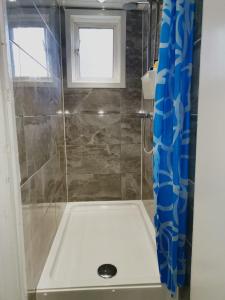 a bathroom with a shower with a toilet and a window at City Budget Guesthouse in London