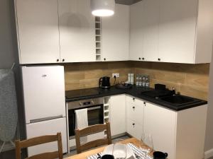 une cuisine avec des armoires blanches, une table et un évier dans l'établissement CR Cichy Apartament w Centrum, à Białystok