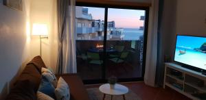 a living room with a television and a view of the ocean at Cantinho do Sol - Sea view, Quiet, Cozy and Relaxing Flat in Armação de Pêra