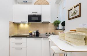 a kitchen with white cabinets and a sink and a table at Vittoria Suite in Rome