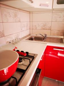 Il comprend une cuisine équipée d'une cuisinière, d'un évier et de placards rouges. dans l'établissement Apartman "Sabine red" with pool, à Omišalj