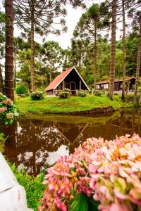 uma casa no meio de um lago com flores em Hotel Fazenda Floresta Negra em Monte Verde