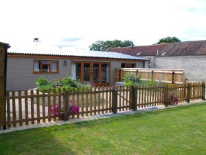 a wooden fence in front of a house with flowers at The Old Cowstall in Somerton