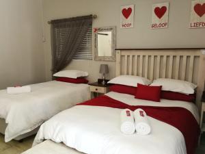 1 dormitorio con 2 camas y almohadas rojas y blancas en Kalahari Rus, en Upington