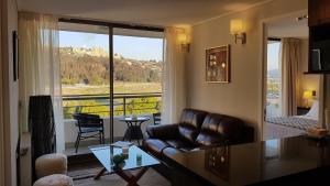 a living room with a couch and a large window at Alto Sporting Apartments in Viña del Mar
