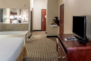 a hotel room with a bed and a flat screen tv at Red Lion Inn & Suites Mineral Wells in Mineral Wells