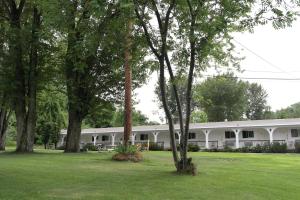 un gran edificio blanco con árboles delante de él en Ray Lyn Motel en Trail