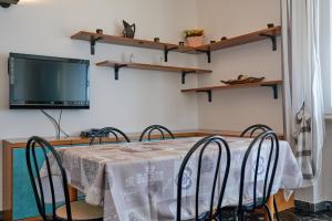 une salle à manger avec une table, des chaises et une télévision dans l'établissement Casa Manu, à Brenzone