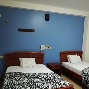 a room with two beds and a blue wall at Hotel Murcia in Guayaquil