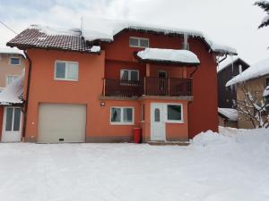 a red house with snow on the roof at Apartman Vesna in Kupres